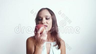 美丽的年轻微笑的女人吃红苹果水果。 慢动作。 孤立在白色背景上。 3840x2160